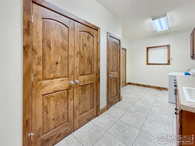 1241 S Sherman Ave, Holyoke, CO 80734 - clothes washing area with cabinet space, washer and clothes dryer, baseboards, and light tile patterned floors