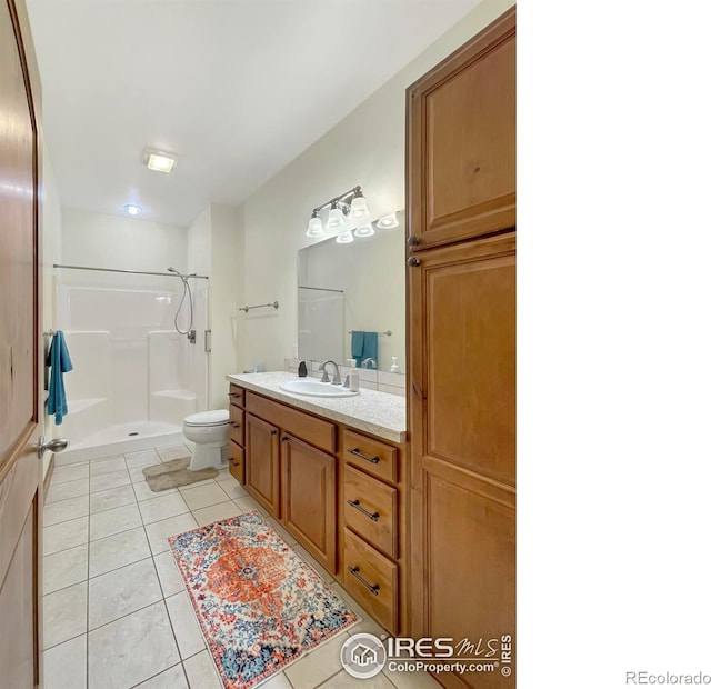 bathroom featuring a shower, vanity, tile patterned floors, and toilet