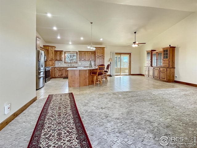 kitchen featuring a center island, lofted ceiling, ceiling fan, appliances with stainless steel finishes, and tasteful backsplash