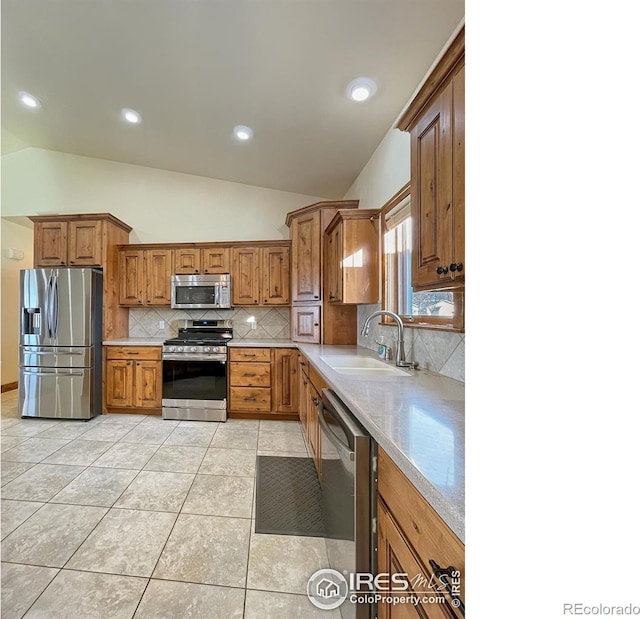 kitchen featuring decorative backsplash, appliances with stainless steel finishes, sink, lofted ceiling, and light tile patterned flooring