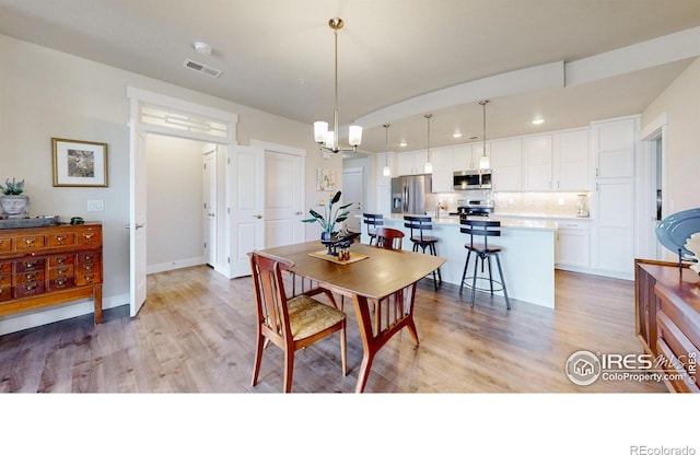 dining room with an inviting chandelier and light hardwood / wood-style flooring