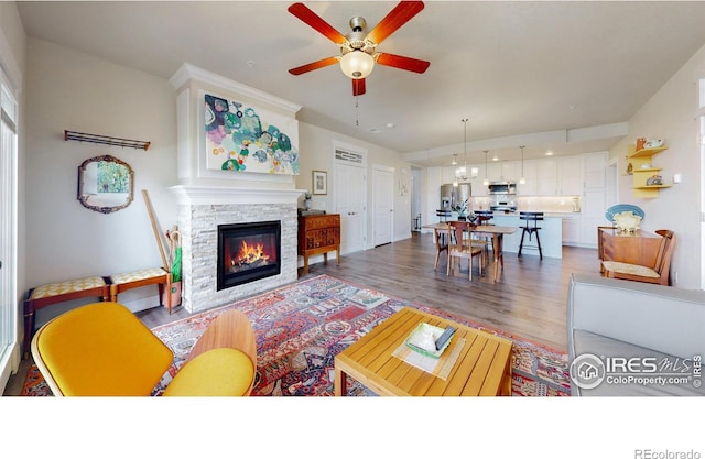 6634 Crystal Downs Dr Unit 104, Windsor, CO 80550 - living area with wood finished floors, a ceiling fan, and a stone fireplace