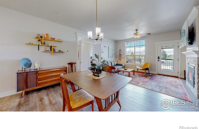6634 Crystal Downs Dr Unit 104, Windsor, CO 80550 - dining room with wood finished floors, a ceiling fan, a fireplace, a chandelier, and baseboards