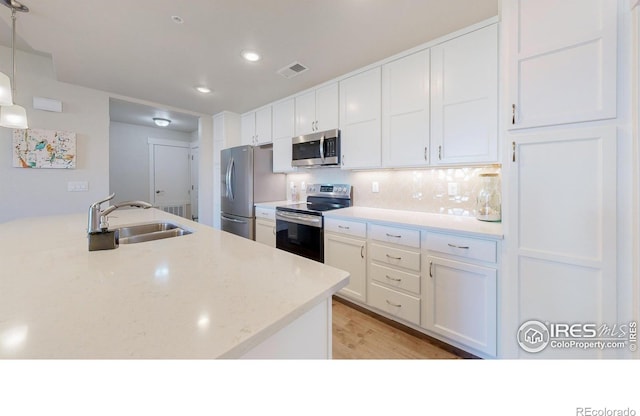 6634 Crystal Downs Dr Unit 104, Windsor, CO 80550 - kitchen featuring stainless steel appliances, white cabinetry, a sink, backsplash, and light wood finished floors