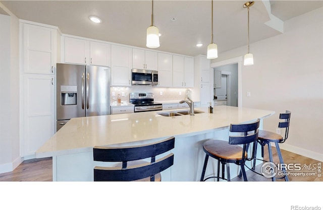 kitchen featuring appliances with stainless steel finishes, sink, pendant lighting, and a kitchen island with sink