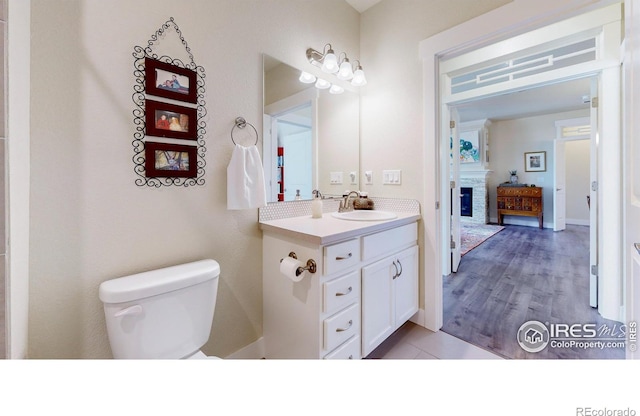 6634 Crystal Downs Dr Unit 104, Windsor, CO 80550 - bathroom featuring toilet, vanity, and a glass covered fireplace