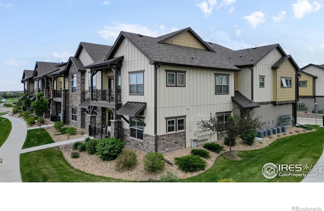 6634 Crystal Downs Dr Unit 104, Windsor, CO 80550 - view of side of home featuring board and batten siding, a shingled roof, stone siding, and a yard