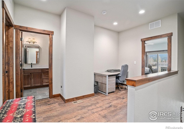 home office with light hardwood / wood-style flooring and sink