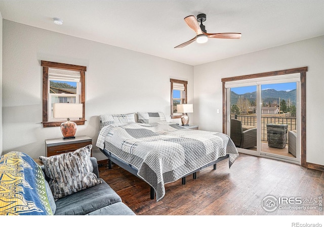 bedroom featuring dark hardwood / wood-style flooring, a mountain view, access to exterior, and ceiling fan