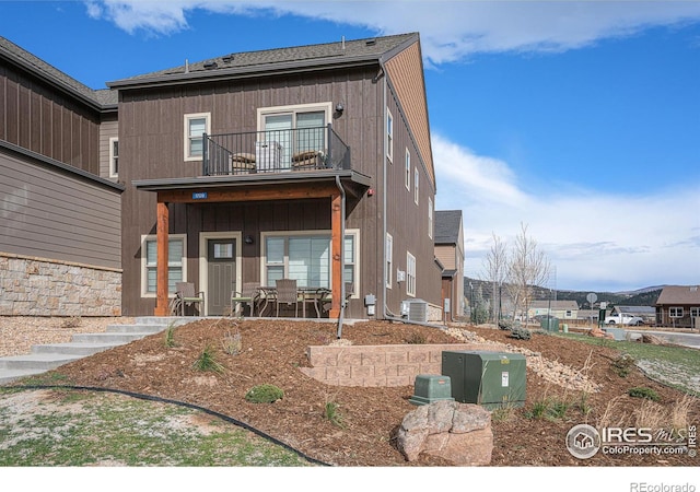 view of front of house with a balcony, central AC, and a patio area