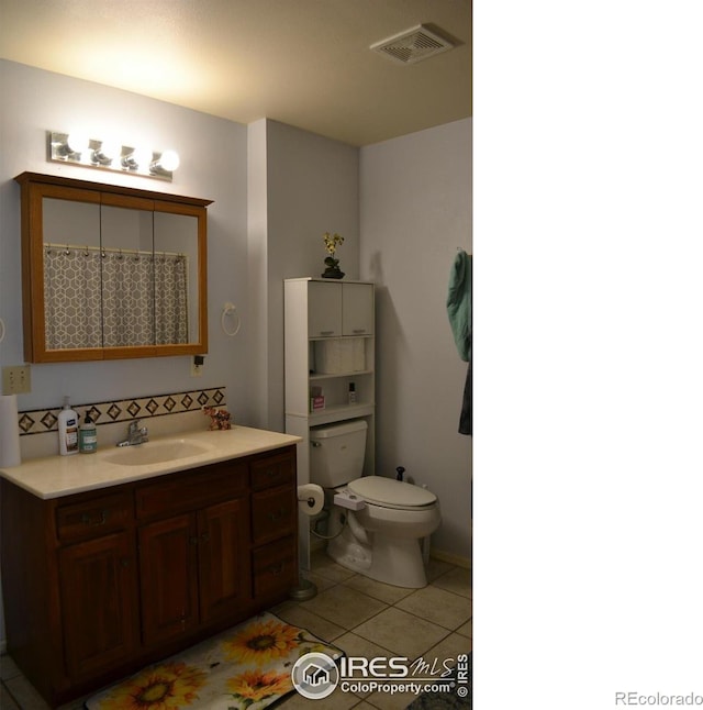 bathroom with toilet, vanity, and tile patterned flooring