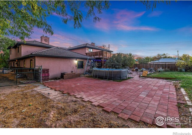 patio terrace at dusk featuring a fenced in pool