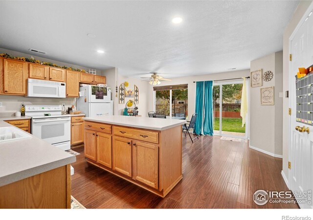 kitchen featuring white appliances, a center island, dark hardwood / wood-style flooring, and ceiling fan