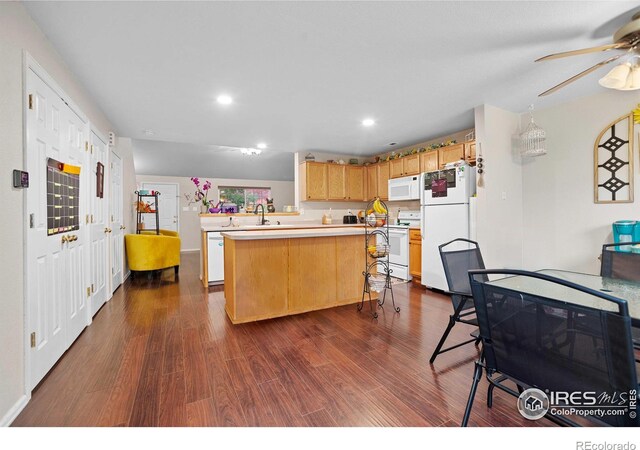 kitchen with white appliances, a center island, kitchen peninsula, a kitchen breakfast bar, and dark hardwood / wood-style floors