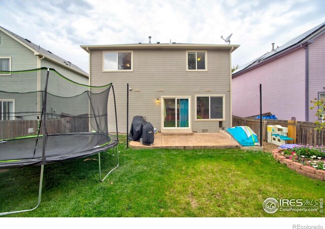 back of house with a patio, a lawn, and a trampoline