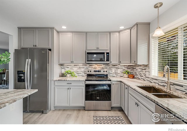 kitchen with light stone countertops, appliances with stainless steel finishes, sink, and gray cabinets