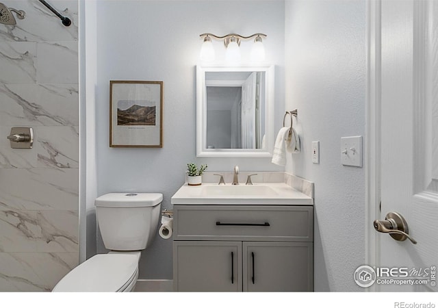 bathroom with vanity, tiled shower, and toilet