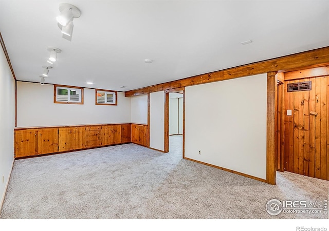 basement featuring wooden walls and light colored carpet