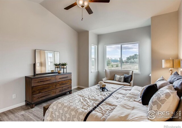 bedroom featuring lofted ceiling, ceiling fan, baseboards, and light wood-style floors