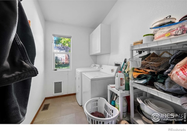 clothes washing area with independent washer and dryer, cabinets, and light tile patterned floors