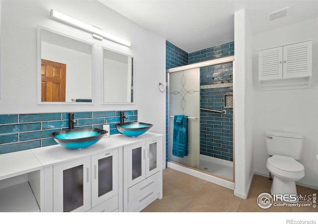 bathroom with a shower with door, tasteful backsplash, toilet, vanity, and tile patterned flooring