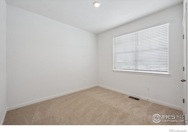 empty room featuring carpet, visible vents, and baseboards