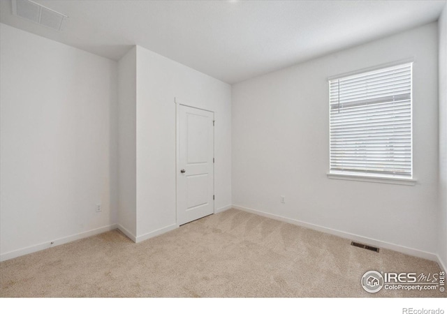 carpeted empty room featuring visible vents and baseboards