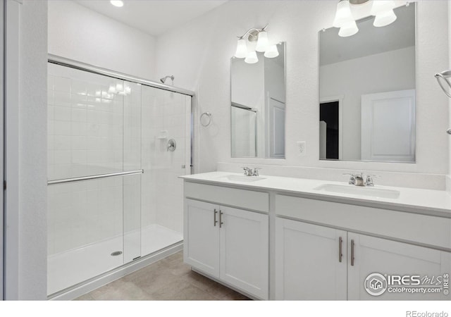 full bath with double vanity, a stall shower, tile patterned flooring, and a sink