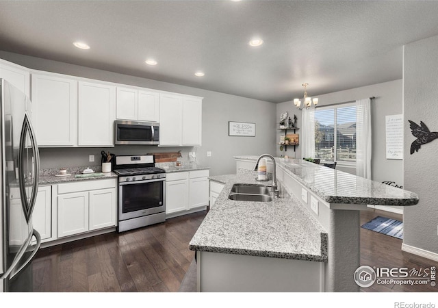 kitchen with appliances with stainless steel finishes, sink, white cabinets, dark hardwood / wood-style floors, and a kitchen island with sink