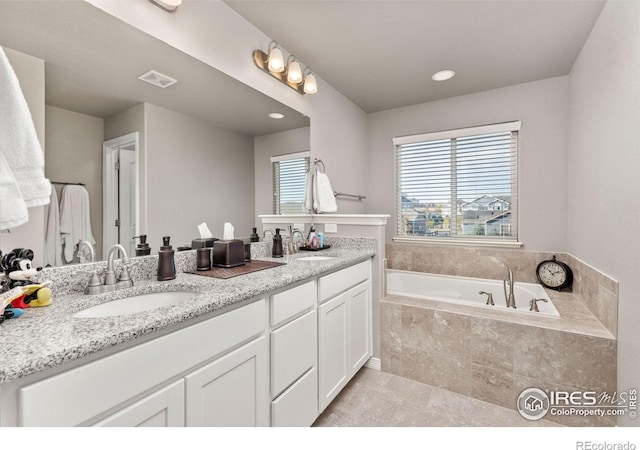 bathroom featuring vanity and tiled tub