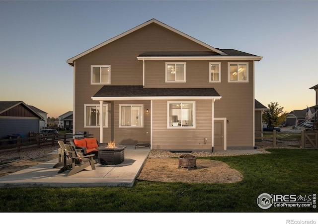 back house at dusk with a patio area, a fire pit, and a lawn