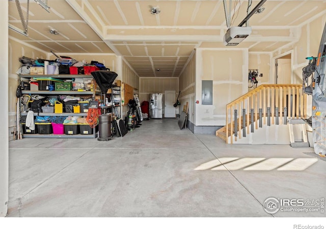 garage with a garage door opener, electric panel, and stainless steel refrigerator with ice dispenser