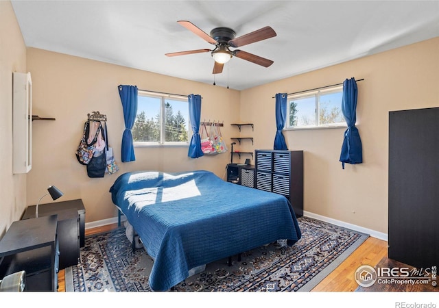 bedroom featuring ceiling fan, hardwood / wood-style flooring, and multiple windows