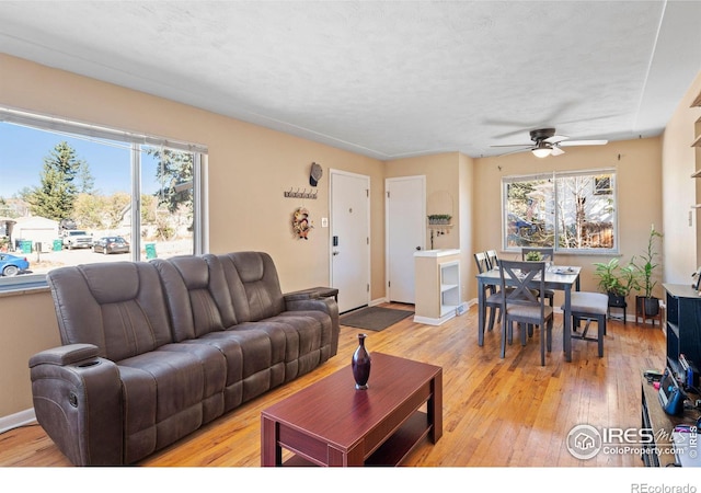 living room featuring light hardwood / wood-style floors, a textured ceiling, and ceiling fan