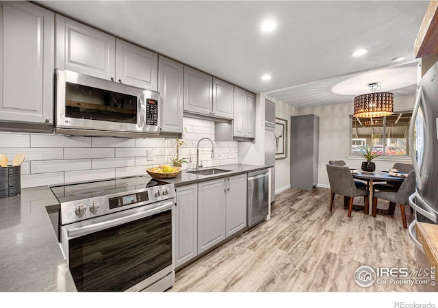 kitchen featuring light hardwood / wood-style flooring, tasteful backsplash, gray cabinets, appliances with stainless steel finishes, and sink