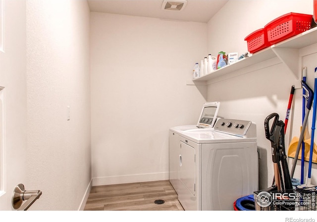 laundry area with light hardwood / wood-style flooring and washing machine and clothes dryer