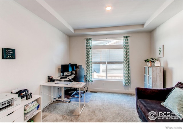 carpeted home office featuring a tray ceiling