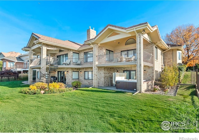 rear view of property featuring a patio area, a lawn, a balcony, and a hot tub