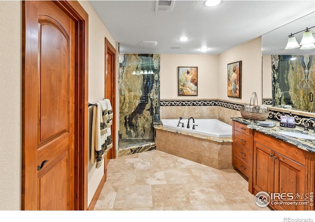 bathroom with vanity, a textured ceiling, and a relaxing tiled tub