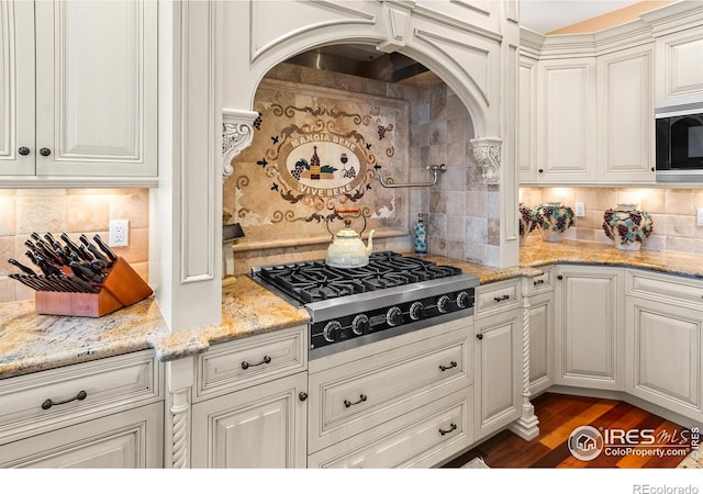 kitchen featuring light stone countertops, stainless steel appliances, decorative backsplash, and dark hardwood / wood-style flooring