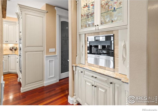 kitchen featuring backsplash, light stone countertops, dark hardwood / wood-style floors, and white cabinets