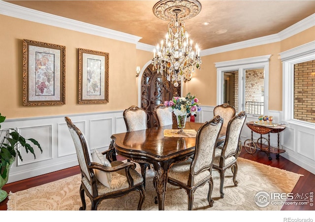 dining space with a notable chandelier, ornamental molding, and hardwood / wood-style floors