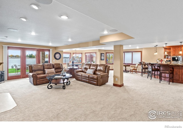 carpeted living room featuring a water view and a textured ceiling