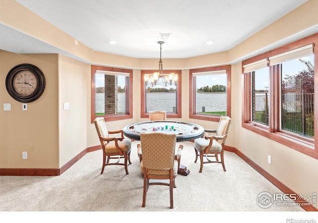 dining space featuring a water view, light carpet, and a notable chandelier