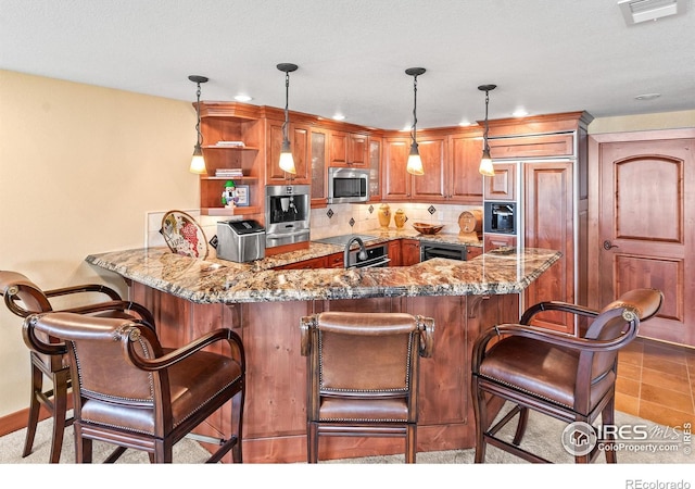 kitchen featuring a breakfast bar area, hanging light fixtures, appliances with stainless steel finishes, and kitchen peninsula