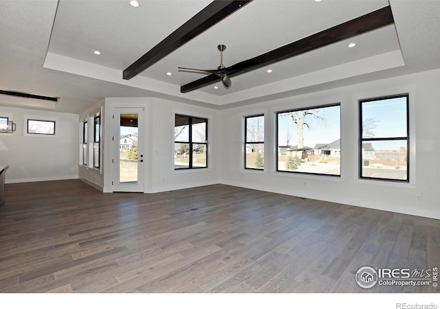 spare room with a raised ceiling, ceiling fan, hardwood / wood-style floors, and beam ceiling