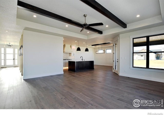 unfurnished living room with beam ceiling, dark hardwood / wood-style floors, and ceiling fan