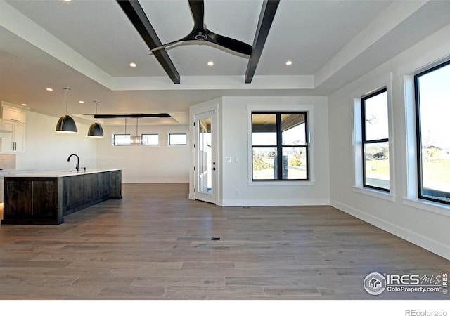 kitchen with dark brown cabinets, a kitchen island with sink, sink, pendant lighting, and light hardwood / wood-style floors