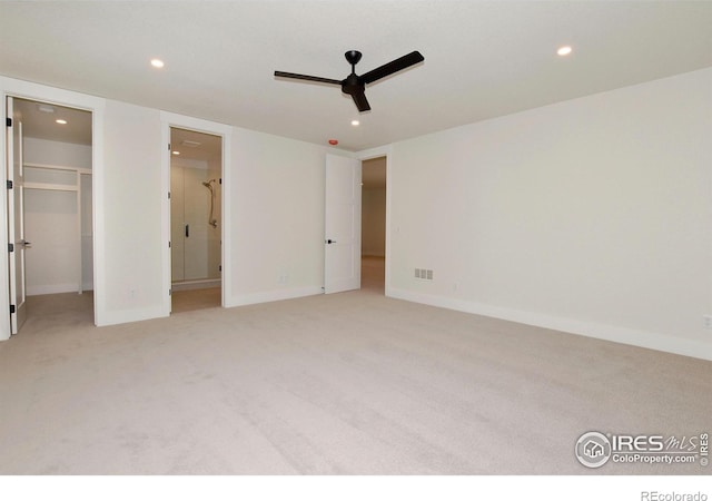 unfurnished bedroom with connected bathroom, a spacious closet, ceiling fan, and light colored carpet