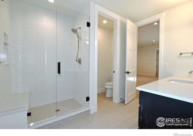 bathroom with tile patterned flooring, vanity, toilet, and a shower with door